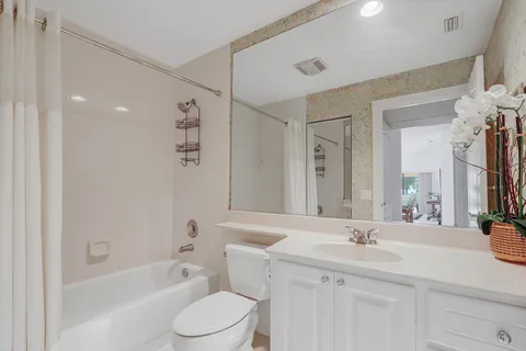 a bathroom with a sink a toilet a mirror a vanity and bathtub