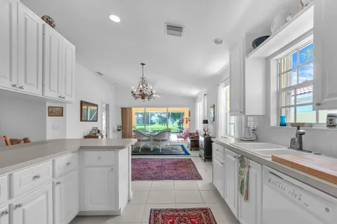 a large kitchen with kitchen island a large window a sink stainless steel appliances and cabinets