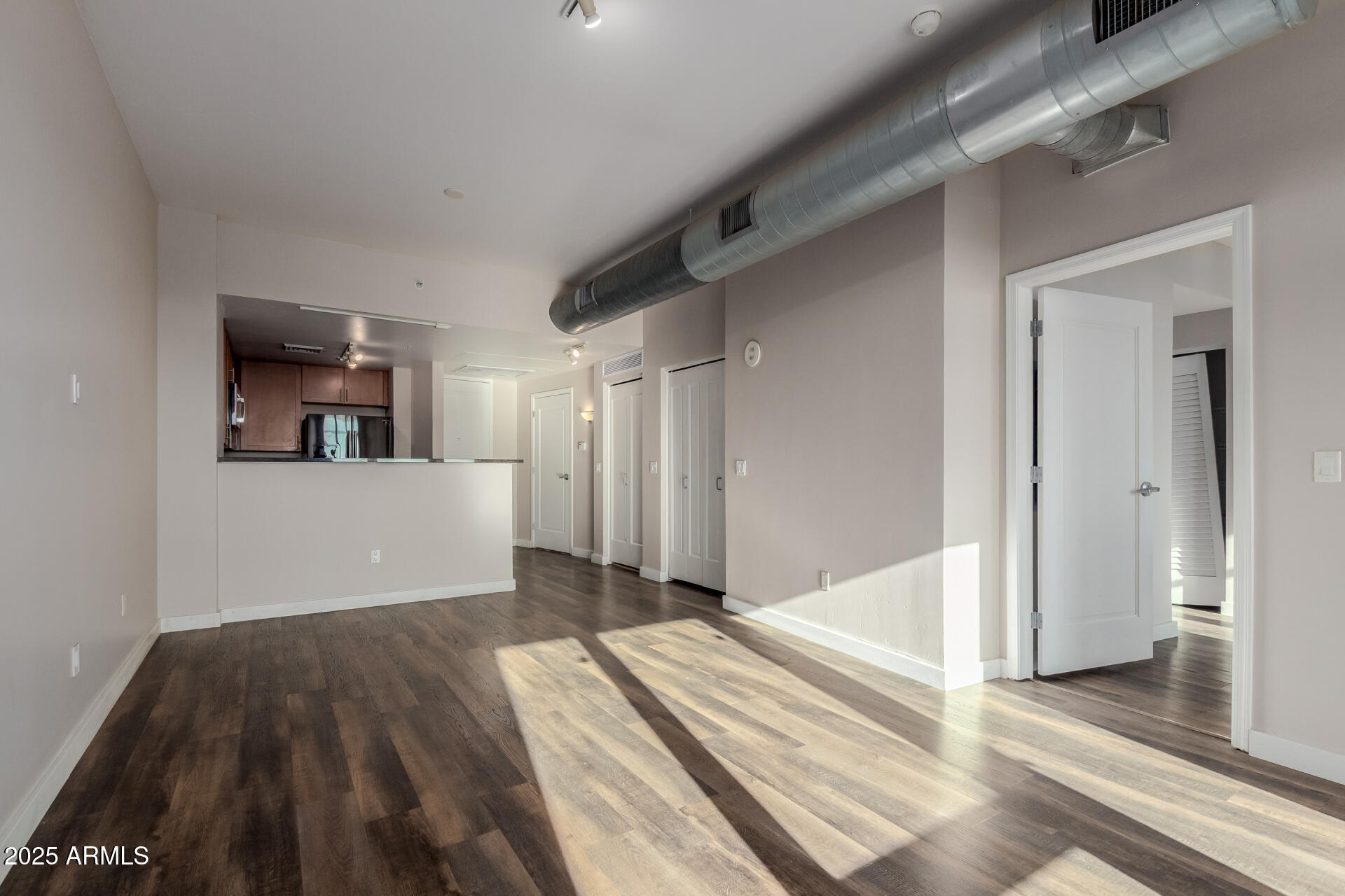 310 South 4th Street, Unit 1902 Phoenix, AZ 85004 - Photo 10 of 37 a view of a bedroom with wooden floor and a kitchen