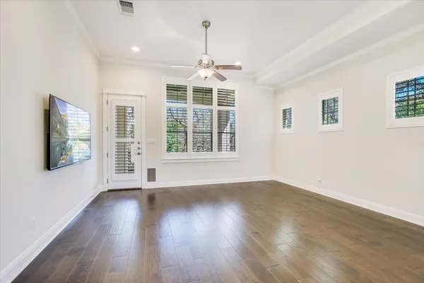 a view of an empty room with wooden floor and a window