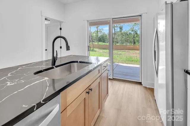 a kitchen with stainless steel appliances granite countertop a refrigerator a stove a microwave and wooden floor