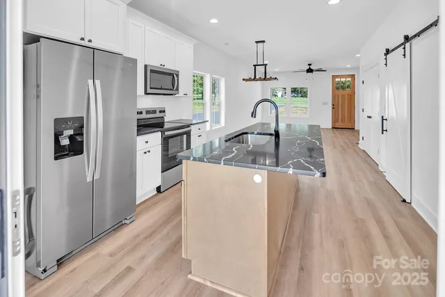 a view of a kitchen with wooden floor a refrigerator a center island and windows