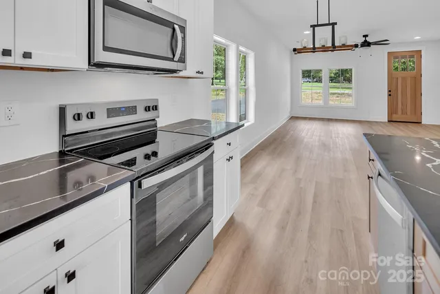 a kitchen with granite countertop a sink a counter top space a stove and wooden floor