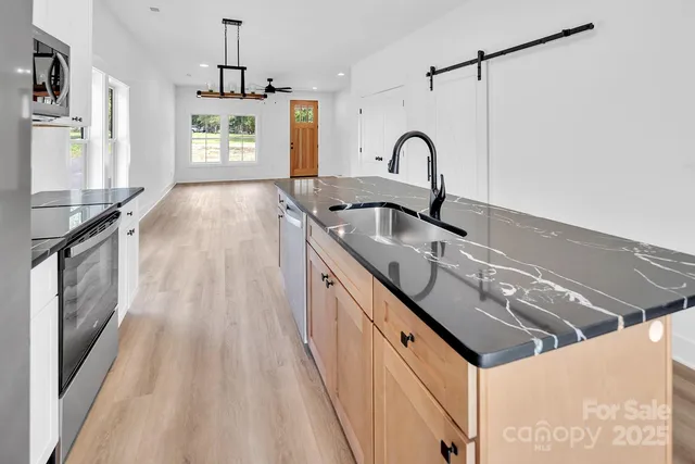 a kitchen with stainless steel appliances granite countertop a refrigerator a stove and a sink with granite countertops