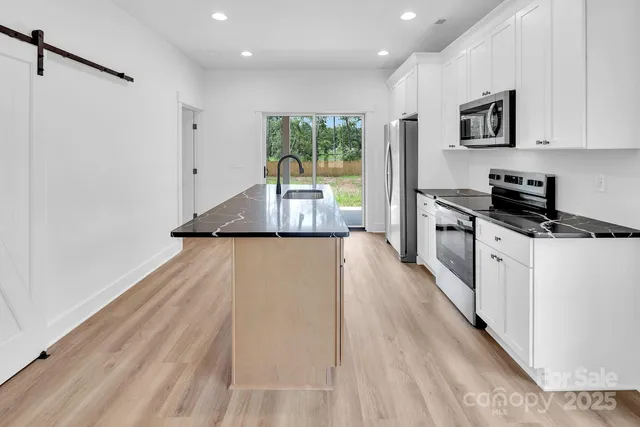 a kitchen with stainless steel appliances granite countertop a refrigerator a stove top oven a sink dishwasher and a microwave oven on the granite countertops