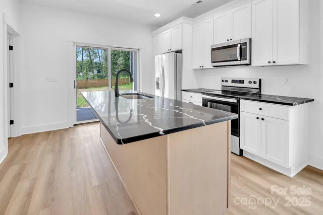a kitchen with stainless steel appliances granite countertop a stove a sink and a refrigerator