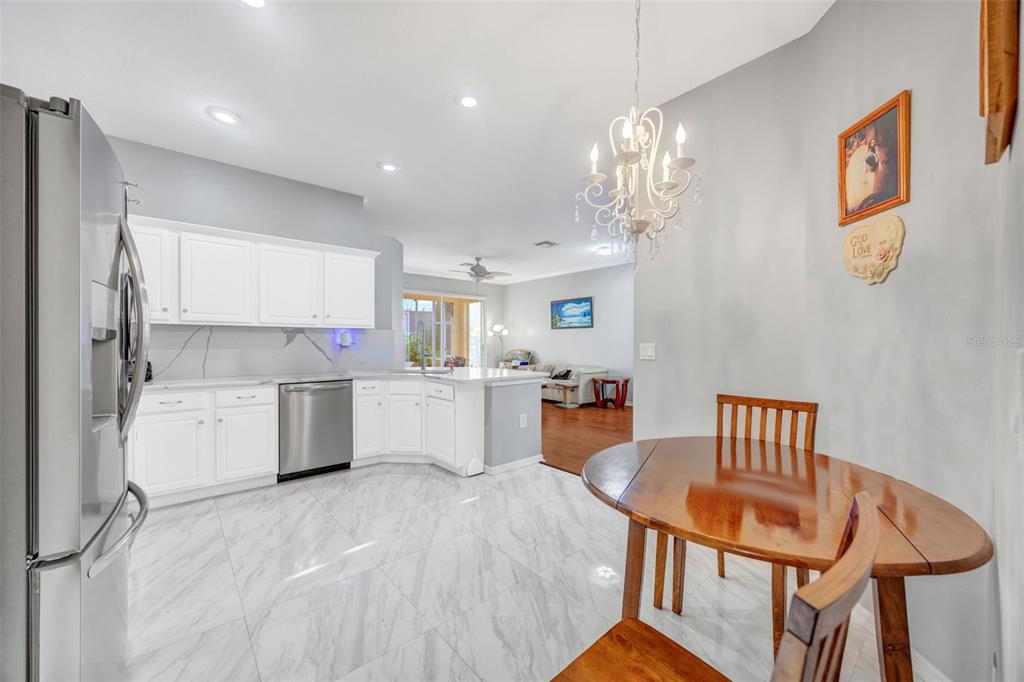 20804 Eustis Road Land O Lakes, FL 34637 - Photo 18 of 65 a kitchen with a refrigerator a sink dishwasher a dining table and chairs with wooden floor
