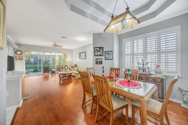 a kitchen with a refrigerator a sink dishwasher a dining table and chairs with wooden floor