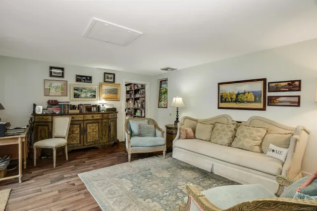 a living room with furniture kitchen view and a wooden floor
