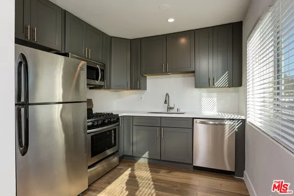 a kitchen with stainless steel appliances granite countertop a refrigerator a sink a stove a microwave and cabinets