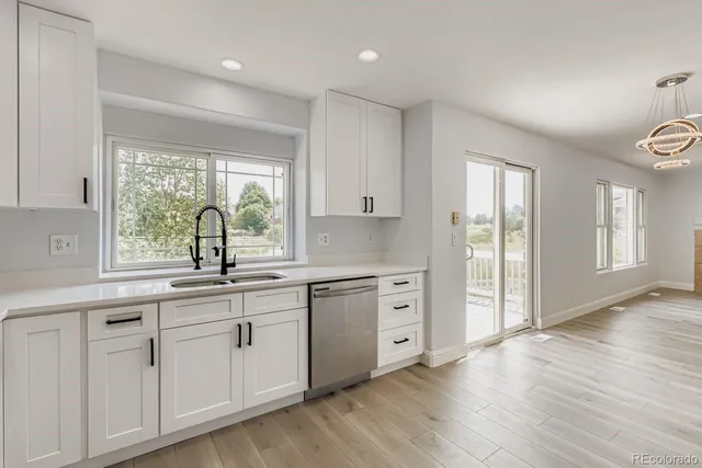 a kitchen with white cabinets and wooden floors