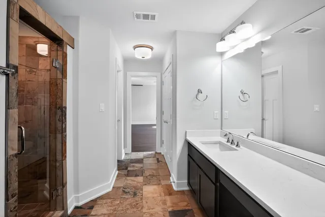 a spacious bathroom with a double vanity sink a large mirror and shower