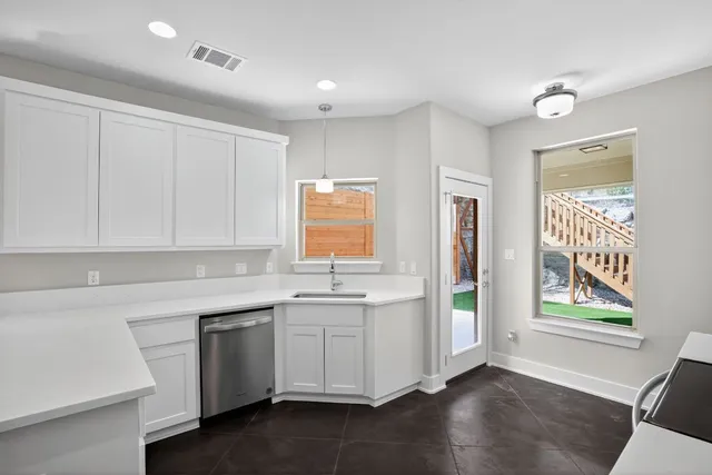 a kitchen with a sink cabinets stainless steel appliances and a window