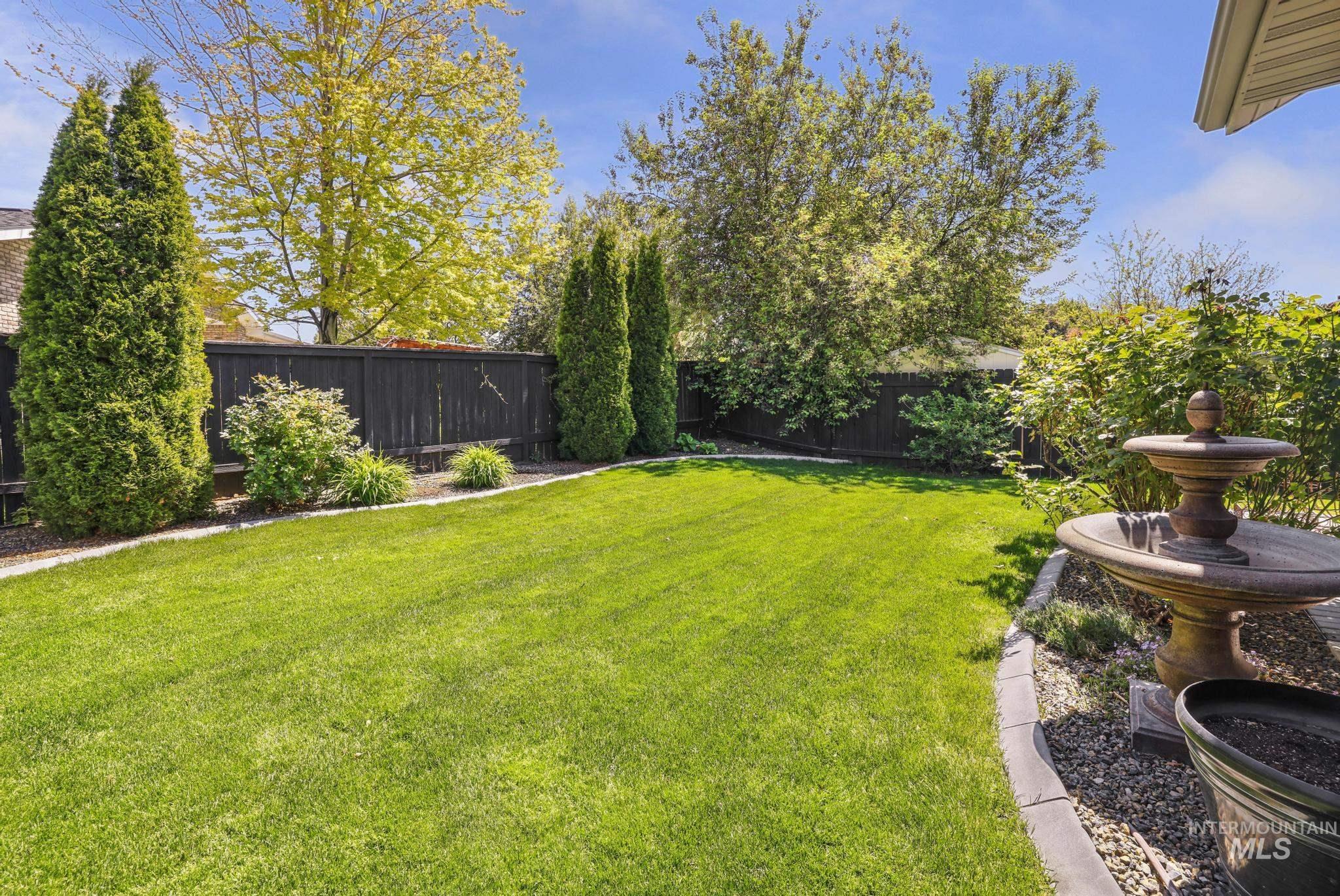 1937 Tamarack Loop Twin Falls, ID 83301 - Photo 42 of 50 Expansive backyard featuring a lush lawn, mature trees, and a decorative fountain
