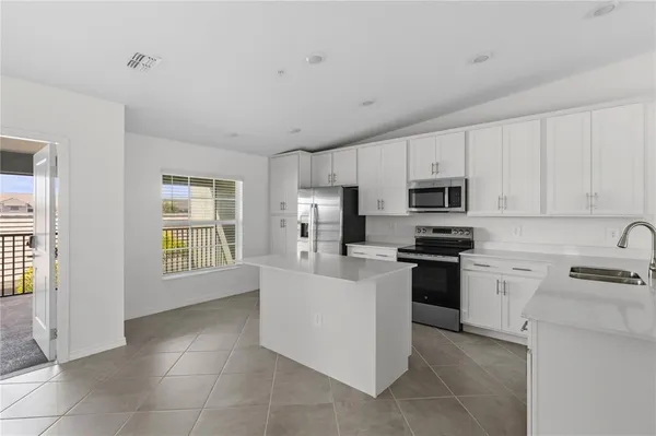 a kitchen with stainless steel appliances granite countertop a stove top oven a sink a refrigerator and white cabinets