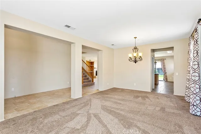 an empty room with kitchen view and wooden floor