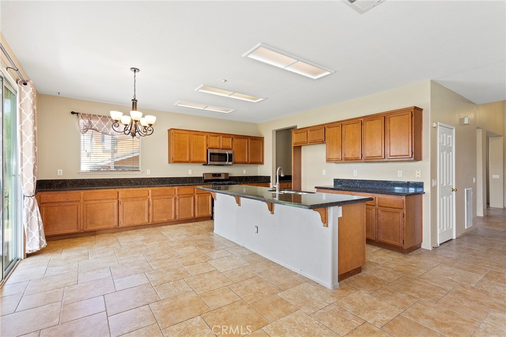 8061 Palm View Lane Riverside, CA 92508 - Photo 4 of 23 a large kitchen with granite countertop a stove a sink dishwasher and a refrigerator