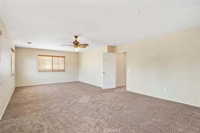 an empty room with a chandelier fan and windows