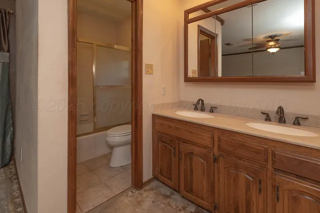 a bathroom with a double vanity sink and mirror with toilet