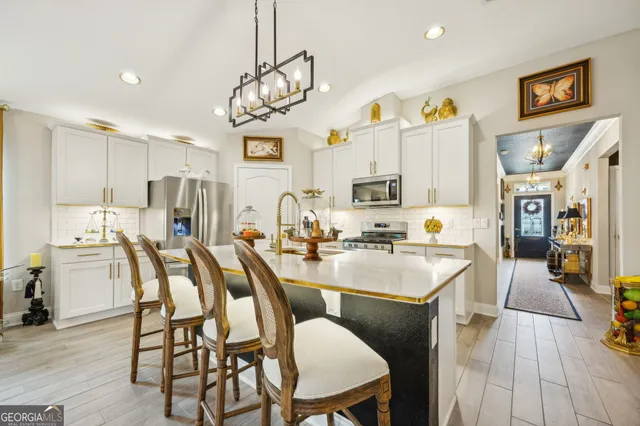 a kitchen with stainless steel appliances kitchen island granite countertop a table chairs and a refrigerator