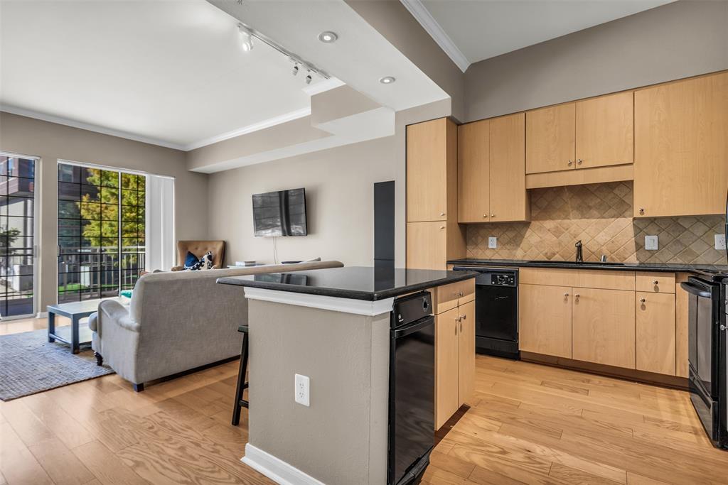 3225 Turtle Creek Boulevard, Unit 10 Dallas, TX 75219 - Photo 37 of 38 Kitchen with light brown cabinets, ornamental molding, open floor plan, a kitchen bar, and light wood-style flooring