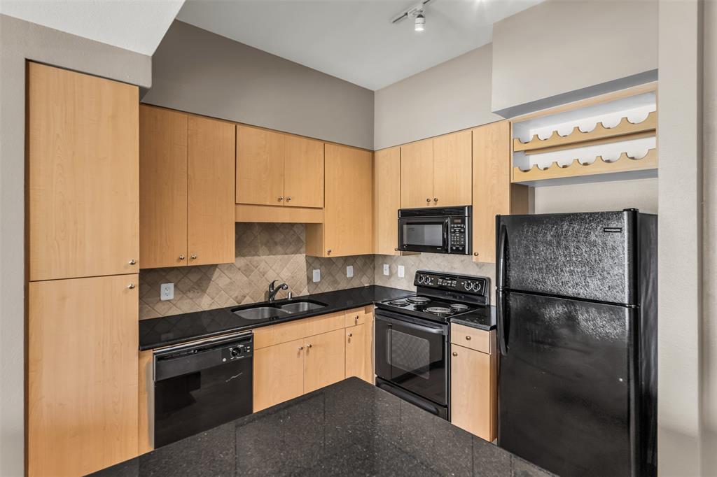 3225 Turtle Creek Boulevard, Unit 10 Dallas, TX 75219 - Photo 15 of 38 Kitchen with black appliances, light brown cabinets, dark stone counters, decorative backsplash, and track lighting
