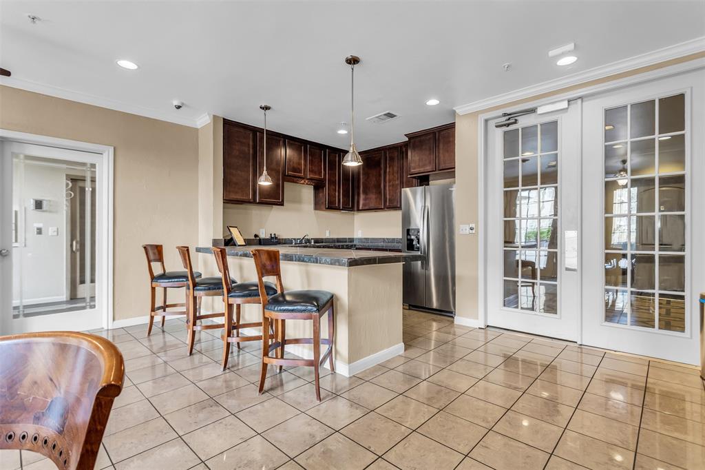 3225 Turtle Creek Boulevard, Unit 10 Dallas, TX 75219 - Photo 32 of 38 Kitchen with a kitchen breakfast bar, dark brown cabinets, hanging light fixtures, tile countertops, and stainless steel fridge with ice dispenser