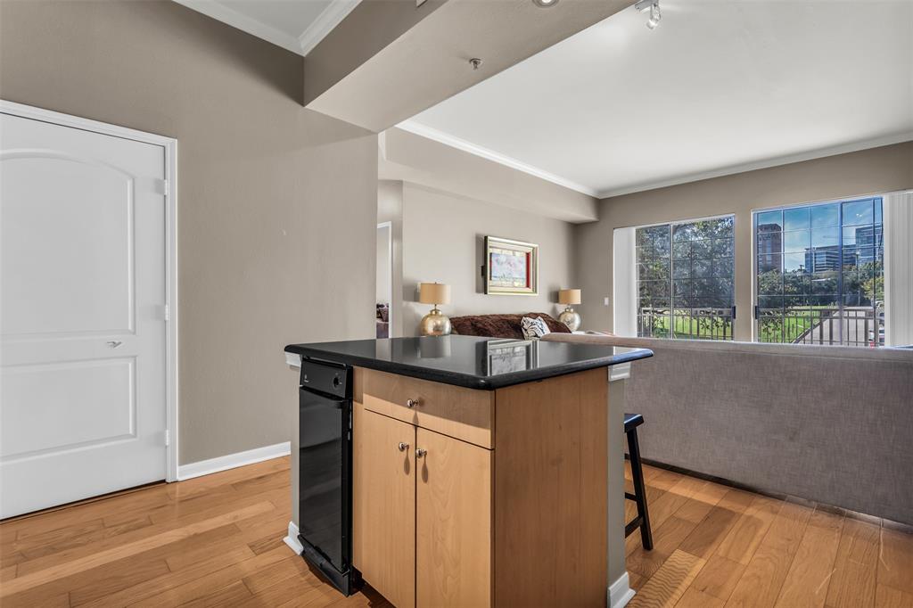 3225 Turtle Creek Boulevard, Unit 10 Dallas, TX 75219 - Photo 38 of 38 Kitchen featuring open floor plan, a breakfast bar area, light wood-style flooring, and crown molding