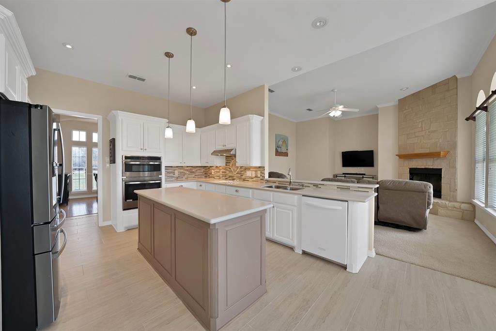 11692 Foutch Road Pilot Point, TX 76258 - Photo 10 of 40 a large kitchen with kitchen island a sink a center island a stove a refrigerator cabinets and living room view