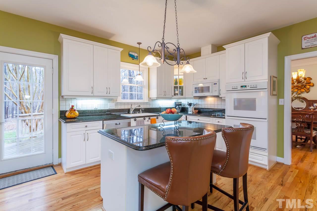 5404 Killarney Hope Drive Raleigh, NC 27613 - Photo 7 of 22 a kitchen with stainless steel appliances granite countertop a stove a sink a refrigerator a dining table and chairs with wooden floor