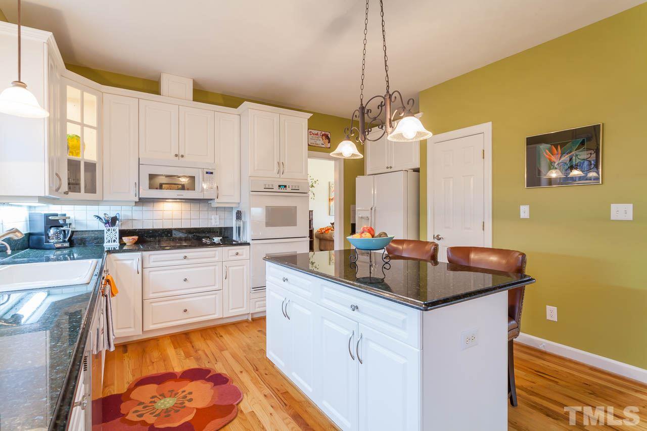 5404 Killarney Hope Drive Raleigh, NC 27613 - Photo 8 of 22 a kitchen with stainless steel appliances granite countertop a sink a stove and a wooden floors