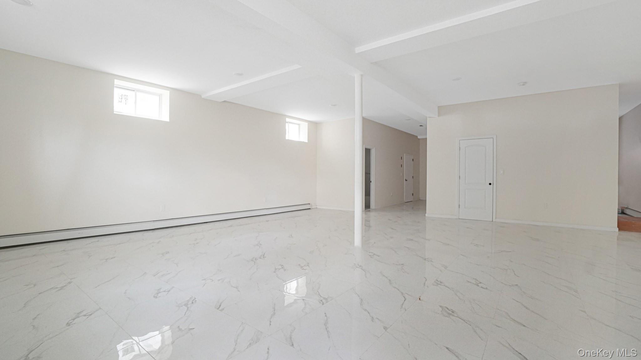 85-02 165th Street Queens, NY 11432 - Photo 23 of 36 Basement with light marble finish floors and a baseboard radiator