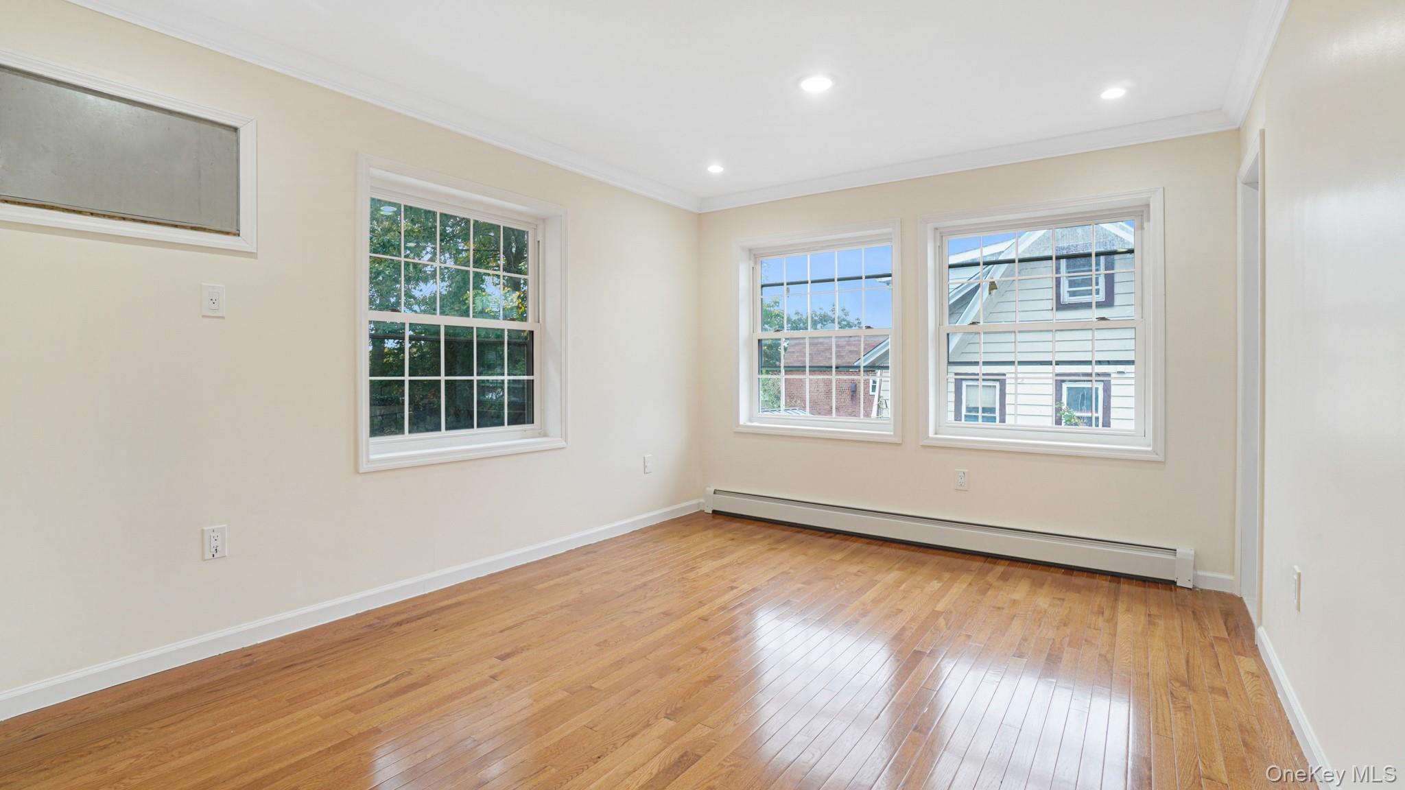 85-02 165th Street Queens, NY 11432 - Photo 31 of 36 Unfurnished room with plenty of natural light, ornamental molding, a baseboard heating unit, light wood-type flooring, and recessed lighting