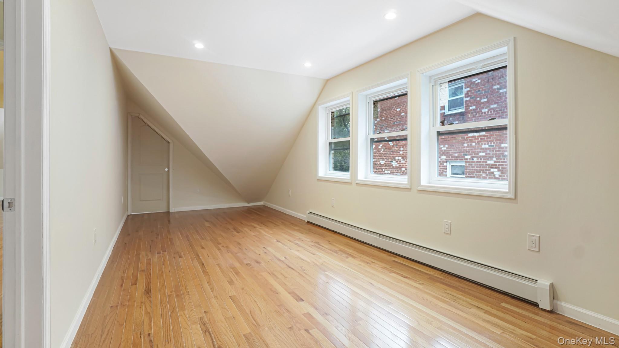 85-02 165th Street Queens, NY 11432 - Photo 35 of 36 Additional living space with a baseboard radiator, vaulted ceiling, light wood-style flooring, and recessed lighting