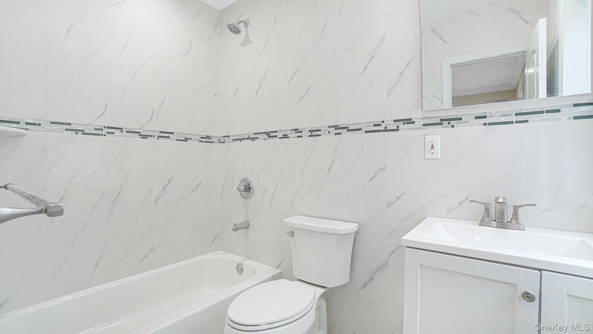 85-02 165th Street Queens, NY 11432 - Photo 9 of 36 Full bath featuring vanity, tile walls, and shower combination