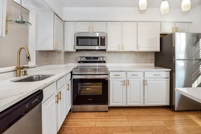 a kitchen with white cabinets and stainless steel appliances