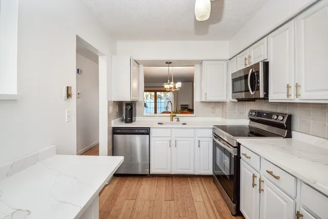 a kitchen with stainless steel appliances white cabinets sink and stove top oven