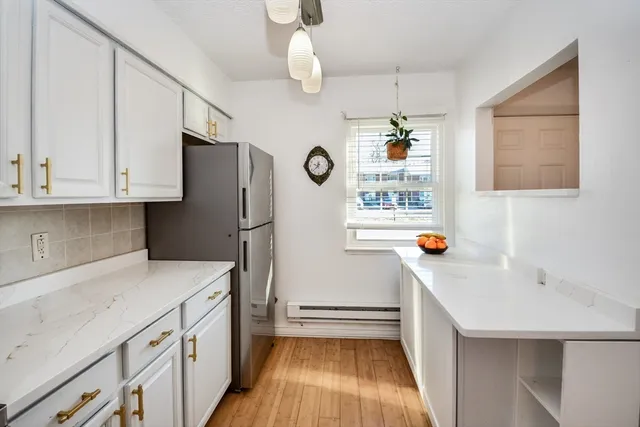 a kitchen with stainless steel appliances granite countertop a refrigerator a sink dishwasher a stove and white countertops with wooden floor