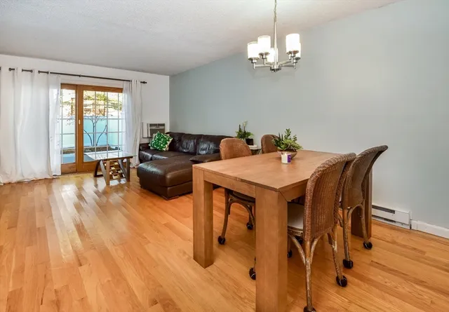 a dining room with wooden floor a chandelier a glass table and chairs