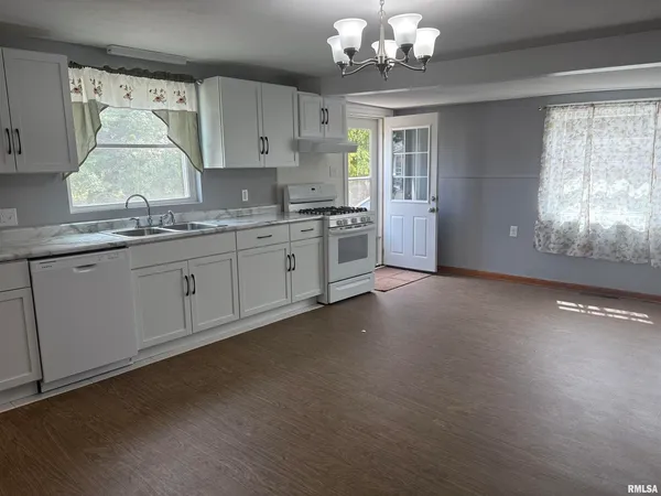 a large kitchen with granite countertop a stove sink and cabinets