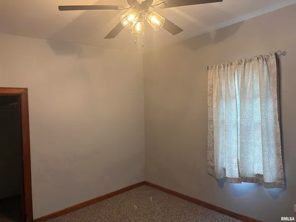 an empty room with a windows and chandelier fan