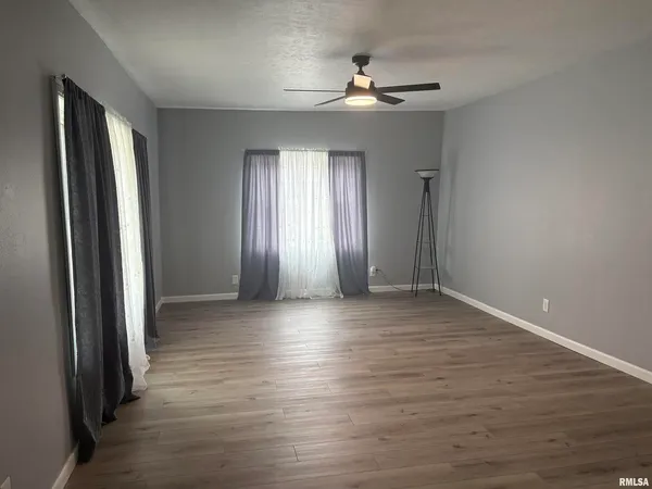 an empty room with wooden floor and windows