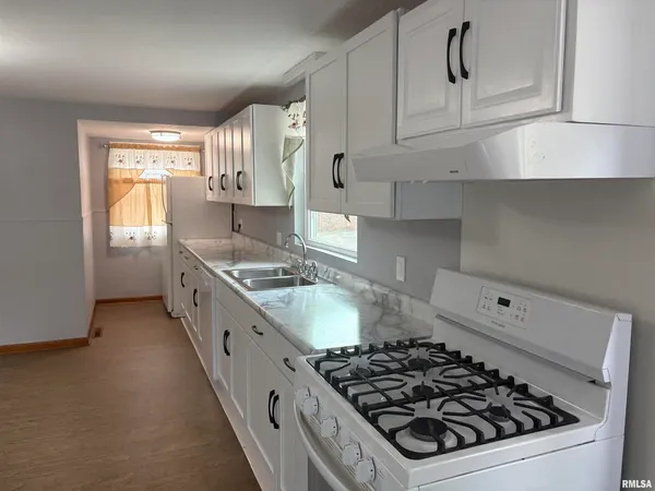 a kitchen with stove a sink and cabinets