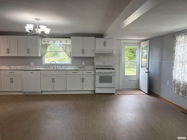 a kitchen with stainless steel appliances a sink a stove a refrigerator a center island and wooden floor