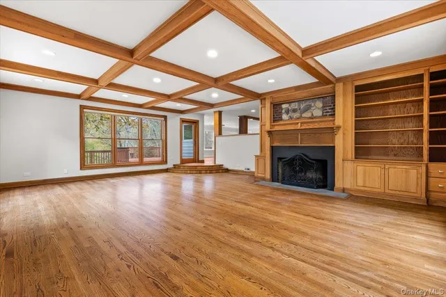 an empty room with wooden floor fireplace and windows