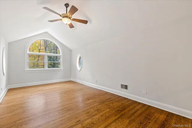 an empty room with wooden floor fan and windows