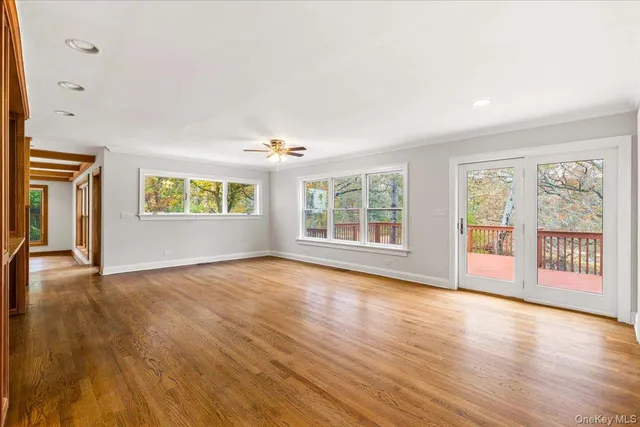 a view of an empty room with a window and wooden floor
