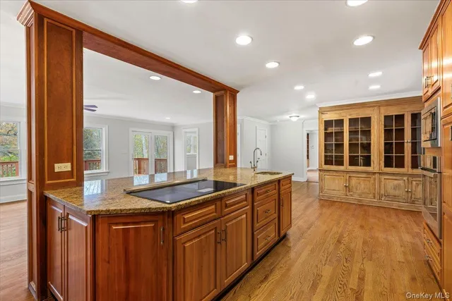 a large kitchen with stainless steel appliances granite countertop a sink and wooden cabinets