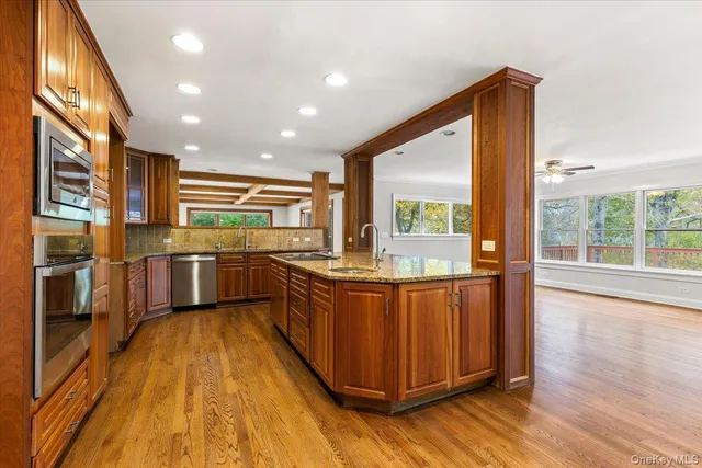 a kitchen with stainless steel appliances granite countertop wooden floors a stove and a sink