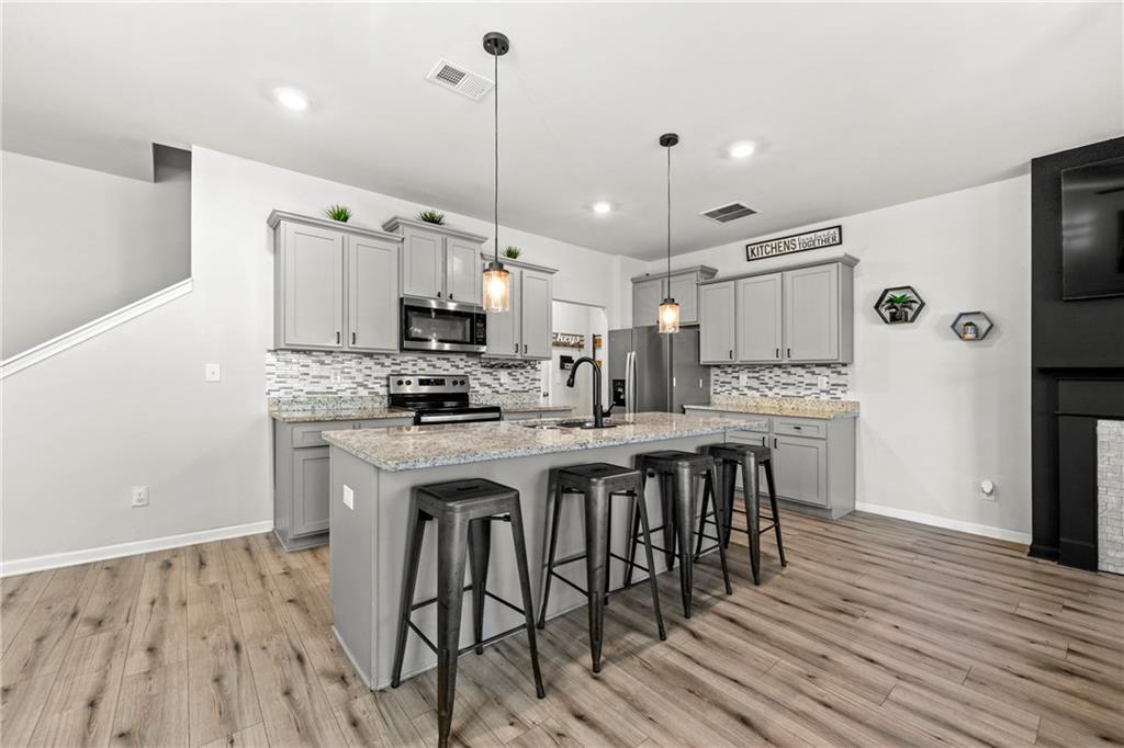 7492 Knoll Hollow Road Lithonia, GA 30058 - Photo 6 of 30 a kitchen with stainless steel appliances kitchen island granite countertop a wooden floor and white cabinets